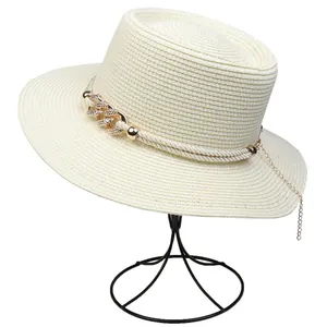 Detailed view of beige straw hat featuring elegant golden chain and rope decoration