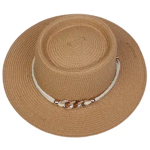 Detail of straw hat texture with white braided rope and golden rhinestone chain