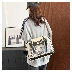 Detail of beige Ita bag with clear PVC window, star decor, and black pompom charm