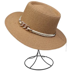 Detail of woven straw hat with pearl rope and gold chain decoration on a stand