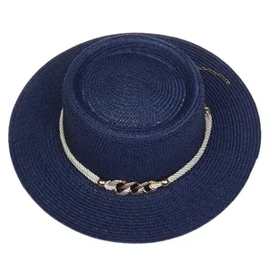 Detail view of navy blue straw boater hat with white rope and gold chain decoration