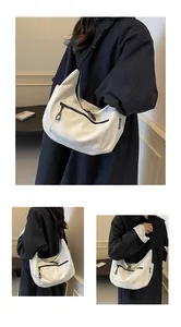 Detail of white moon hobo bag showing black zipper contrast and adjustable shoulder strap