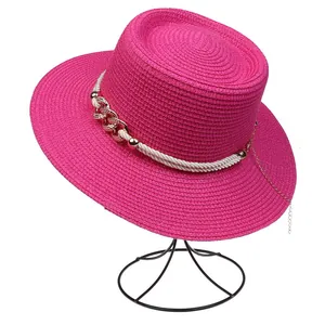 Close-up of fuchsia straw hat with white rope trim and gold chain detail