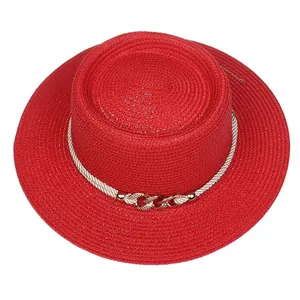 Close-up of a red straw boater hat featuring a white rope band and gold metal chain link