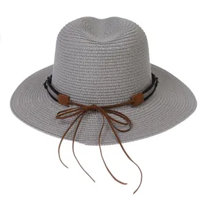 Détail d'un chapeau Panama en paille gris clair avec ruban noir, lacet cuir et nœud long