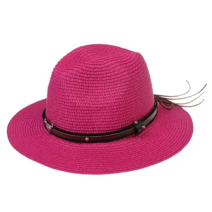 Détail du chapeau Panama fuchsia avec bande en cuir cloutée et pompons bohèmes