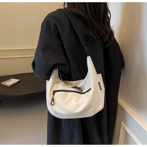Detail of white canvas crescent bag with black zipper pocket and adjustable strap