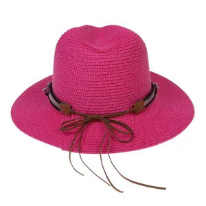 Détail d'un chapeau Panama en paille rose avec nœud marron et perles de décoration