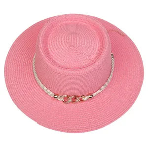 Detail of pink straw hat with white woven rope and golden metal chain decoration