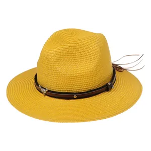 Détail d'un chapeau Panama en paille jaune avec ruban en cuir brun et tête de taureau