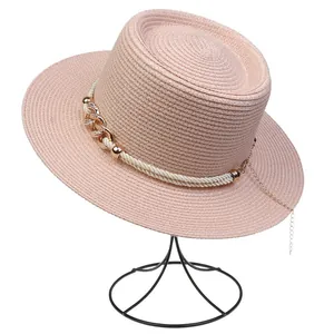 Detail of pink straw boater hat featuring twisted rope and gold chain link decoration