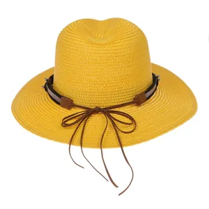 Détail du chapeau Panama jaune avec bande marron à clous et nœud en ruban de cuir