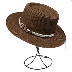 Detailed texture of dark brown straw hat with golden chains and braided rope accent