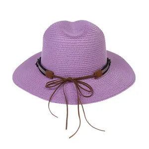 Détail d'un chapeau Panama violet tissé avec texture fine et ruban marron décoratif