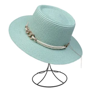 Detail of light blue straw hat featuring white rope trim and gold chain on a black stand