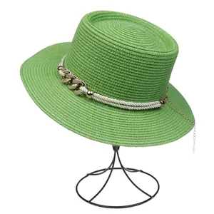 Detail of bright green woven straw hat featuring golden chain and white rope trim