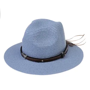 Détail d'un chapeau de paille bleu clair avec bande en cuir et pendentif taureau