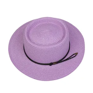 Detail view of purple straw hat featuring textured weave and black woven trim with metal accents
