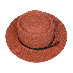 Detail of burnt orange boater straw hat featuring woven texture and black decorative rope
