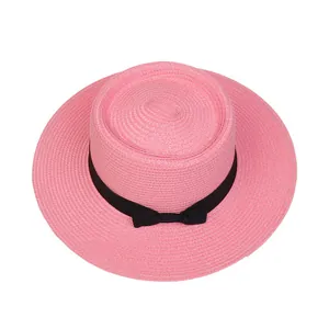 Draufsicht auf rosa Strohhut mit schwarzem Band und Schleife für sonnige Tage