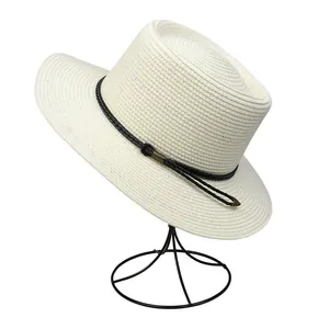 Close-up of summer straw hat with cream weave texture and bronze metal tube detail