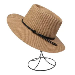 Close-up of woven straw hat featuring a black decorative band and vintage metal buckle