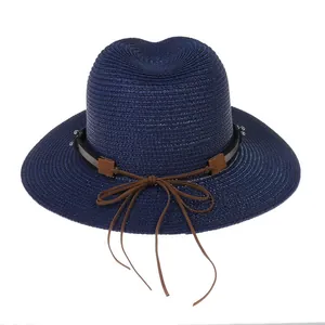 Détail de tissage du chapeau Panama bleu marine avec ruban en cuir brun sur fond blanc