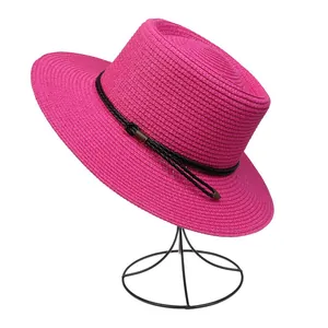 Detail of rose red woven straw hat with black band and metallic buckle accents