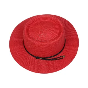 Detail of red boater straw hat featuring woven texture and gold-tipped black rope trim
