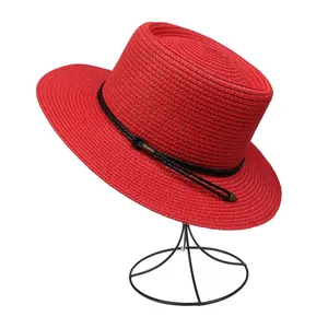 Side view of red straw sun hat with black woven cord detail on a minimalist hat stand