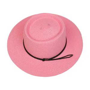 Detailed view of pink straw sun hat texture and black braided rope with metal tips