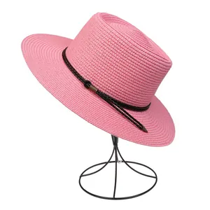 Detailed texture of pink straw sun hat with black woven rope and metal tips