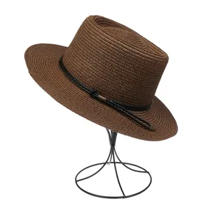 Detailed texture of brown straw hat weave with black braided band and metal buckle