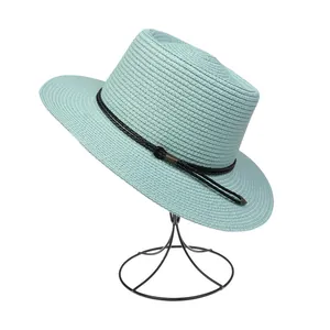 Detail of mint green woven straw hat with black decorative band and metal buckle on stand
