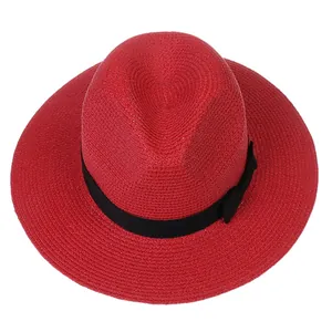 Vue détaillée d'un chapeau Panama en paille rouge avec ruban noir et décoration de nœud