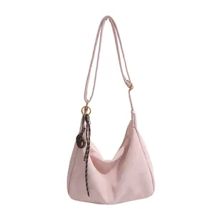 Pink matte hobo shoulder bag with a woven decorative charm and adjustable strap