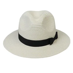 Détail de la texture tressée et du ruban noir avec nœud sur le chapeau panama crème