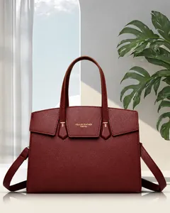Gros plan sur le cuir grainé rouge foncé et la boucle en métal doré du sac à main