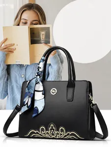 Close-up of black crossbody bag with kangaroo logo and decorative silk scarf on handle