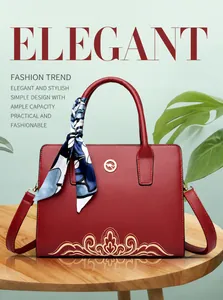 Detail of red leather crossbody bag with golden embroidery and elegant silk scarf decoration