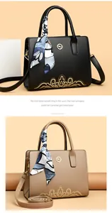 Detail of structured tote bags with golden floral embroidery and decorative silk scarves