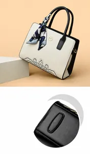 Detail view of beige leather handbag showing bottom wear-resistant patches and floral scarf