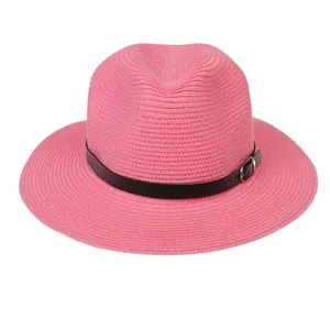 Détail d'un chapeau de paille rose vif avec tissage fin et ceinture en cuir noir