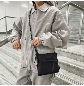 Detail of waterproof nylon crossbody bag with rope strap and yellow accent on streetwear