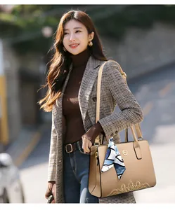 Brown crossbody bag with gold embroidery and silk scarf shown in an outdoor street setting
