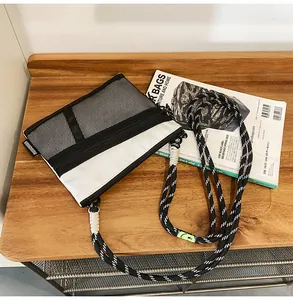 Detail of nylon crossbody bag featuring black mesh pocket and striped shoulder strap