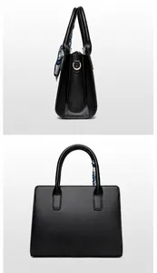 Detail showing high-quality black leather texture with gold metal hardware and chic silk scarf