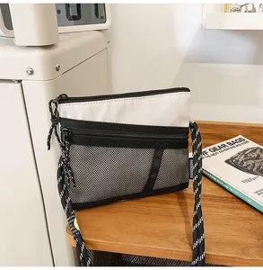 Detail of a black and white nylon crossbody bag featuring mesh pocket and woven rope strap