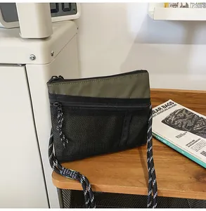 Olive green and black nylon crossbody bag with rope strap on wooden table