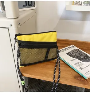 Detail of yellow mesh crossbody bag with paracord strap and smiley face buckle detail
